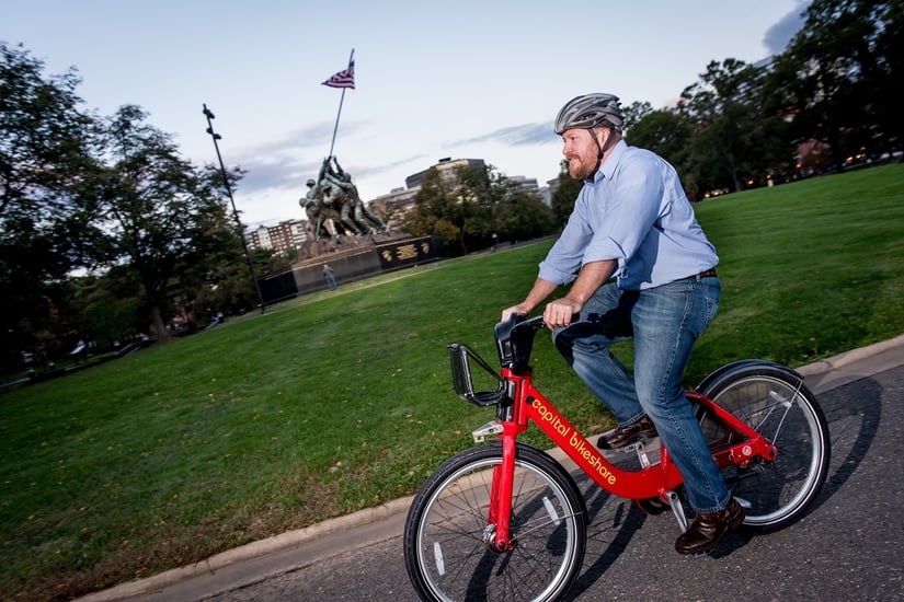 man riding capital bikeshare in front of iwo jima memorial