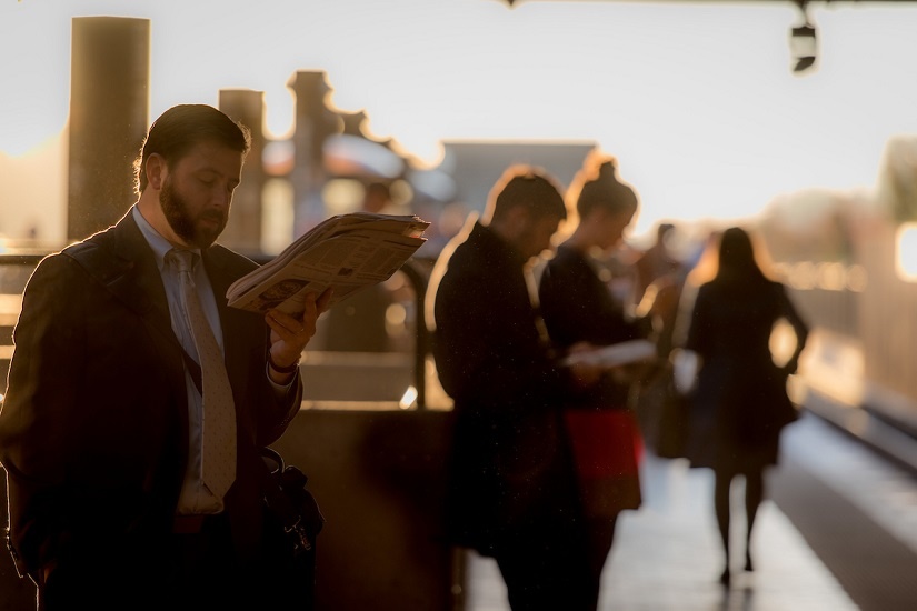 man-reading-paper-metro-platform