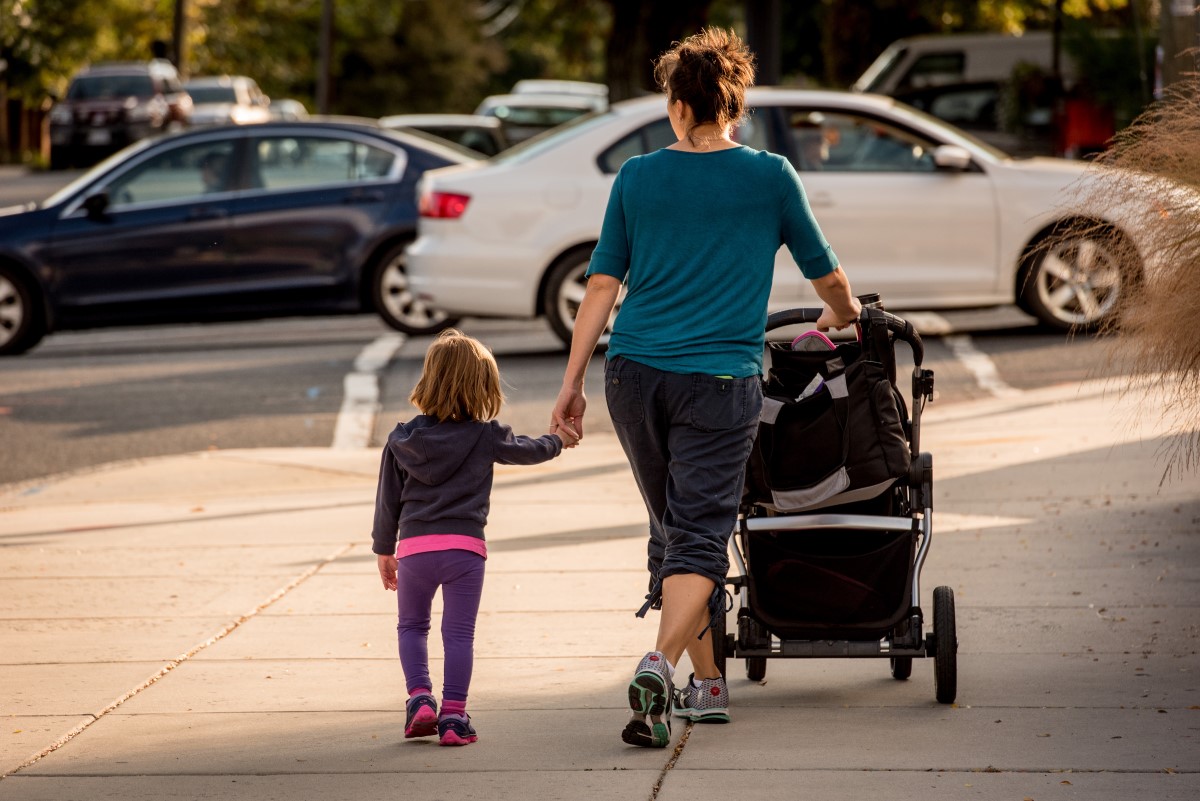 woman-holding-kids-hand-stroller